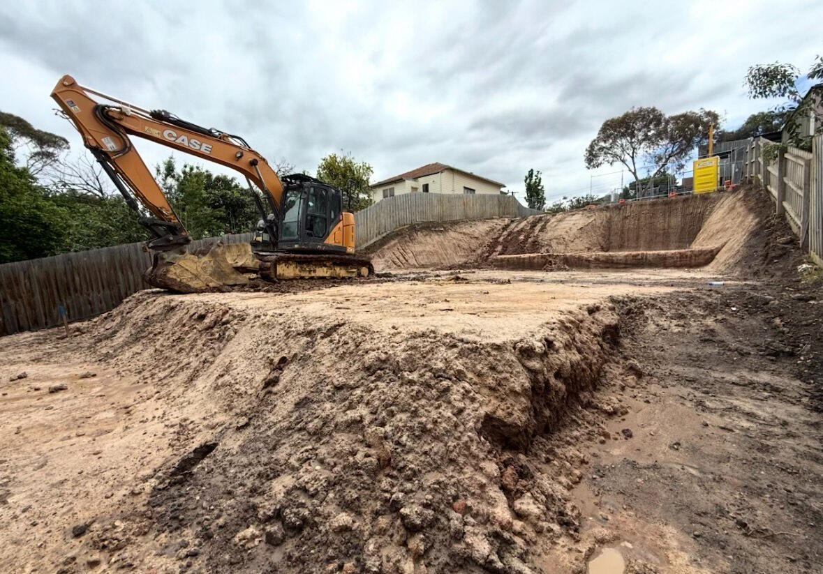 Excavator performing detailed earthworks and trenching during a residential site cut in Melbourne.