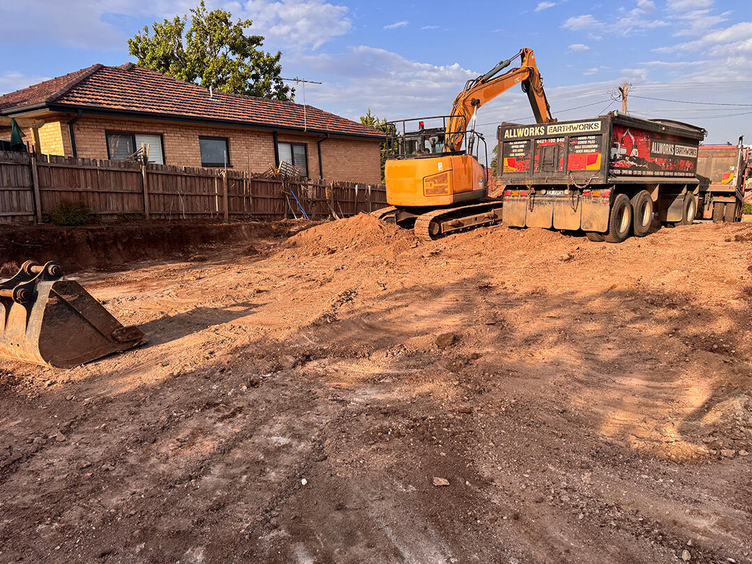 Excavator moving soil and leveling land at a Melbourne site, ensuring accurate site cuts for building projects.